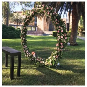 Aro floral boda con rosas rosadas y follaje verde en estructura circular, un diseño elegante y natural ideal para ceremonias, recepciones y fotografías especiales.