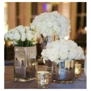 Centro floral blanco con rosas y hortensias en floreros metálicos de distintas alturas, un diseño sofisticado y elegante ideal para recepciones, banquetes y celebraciones.