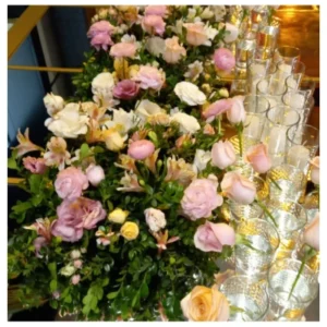 Centro mesa romántico con rosas en tonos pastel, lisianthus y alstroemerias sobre base verde acompañado de velas en recipientes de vidrio, un diseño delicado y elegante ideal para bodas, recepciones y celebraciones especiales.