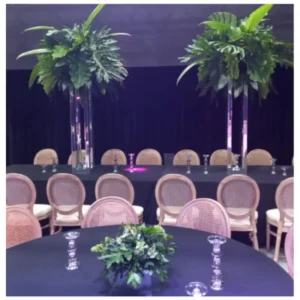Centro mesa verde con follaje tropical en bases cilíndricas espejadas, un diseño moderno, fresco y sofisticado ideal para recepciones, banquetes y celebraciones.