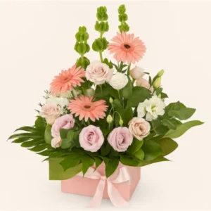 Arreglo floral Dulce Primavera con gerberas rosadas, rosas pastel y lisianthus blancos en caja rosa con lazo, sobre fondo blanco. Composición vertical, equilibrada y elegante, ideal para regalar o decorar.