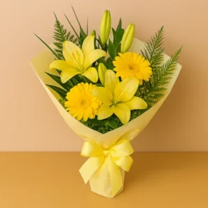 Ramo Día Mamá con lirios amarillos, gerberas, follaje verde, envoltura pastel y lazo satinado, sobre fondo beige y mesa clara. Composición vertical, cálida y armoniosa.