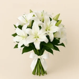 Ramo Lirios Blancos con flores asiáticas abiertas, follaje verde, tallos visibles y lazo blanco de satén, sobre fondo claro. Composición vertical, elegante y serena.