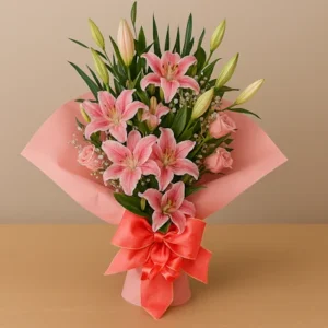 Ramo Lirios Rosados con lirios Stargazer en tonos rosa, gypsophila blanca, capullos verdes, follaje brillante, envoltura rosa y lazo coral satinado, sobre fondo claro. Composición vertical, delicada y armoniosa.