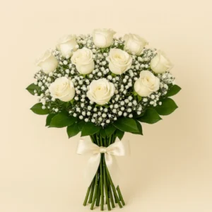 Ramo Rosas Blancas con doce rosas en espiral, gypsophila blanca, follaje verde, tallos visibles y moño satinado marfil, sobre fondo claro. Composición vertical, limpia y elegante.