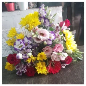 Ramo flores coloridas con rosas rojas, crisantemos amarillos y lisianthus rosados en diseño vibrante y alegre, un arreglo versátil y elegante ideal para regalar y decorar celebraciones.