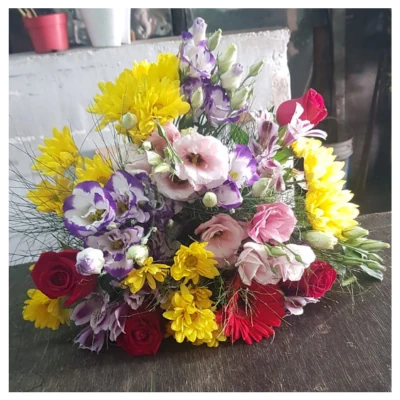 Ramo flores coloridas con rosas rojas, crisantemos amarillos y lisianthus rosados en diseño vibrante y alegre, un arreglo versátil y elegante ideal para regalar y decorar celebraciones.